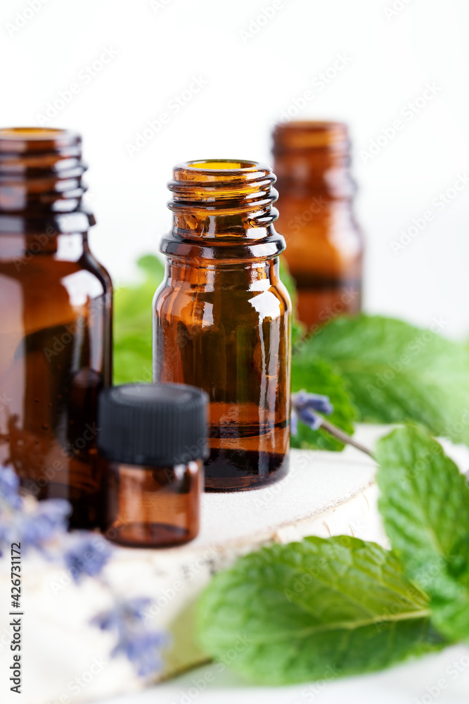 Collection of essential oils in amber bottles, mint leaves and lavender flowers Collection of essential oils in amber bottles, mint leaves and lavender flowers