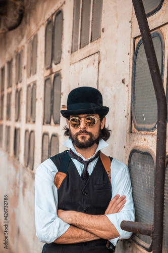 Steampunk. A hero on a river barge surrounded by steel mechanisms. A man with a weapon.