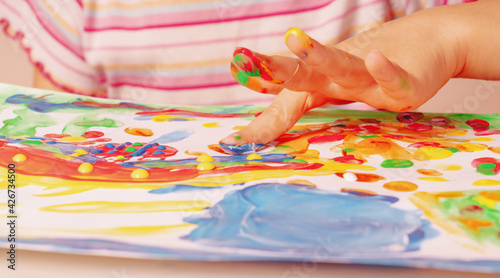 Close up young girl painting with colorful hands and fingers. Art, creativity and painting concept. Horizontal image.