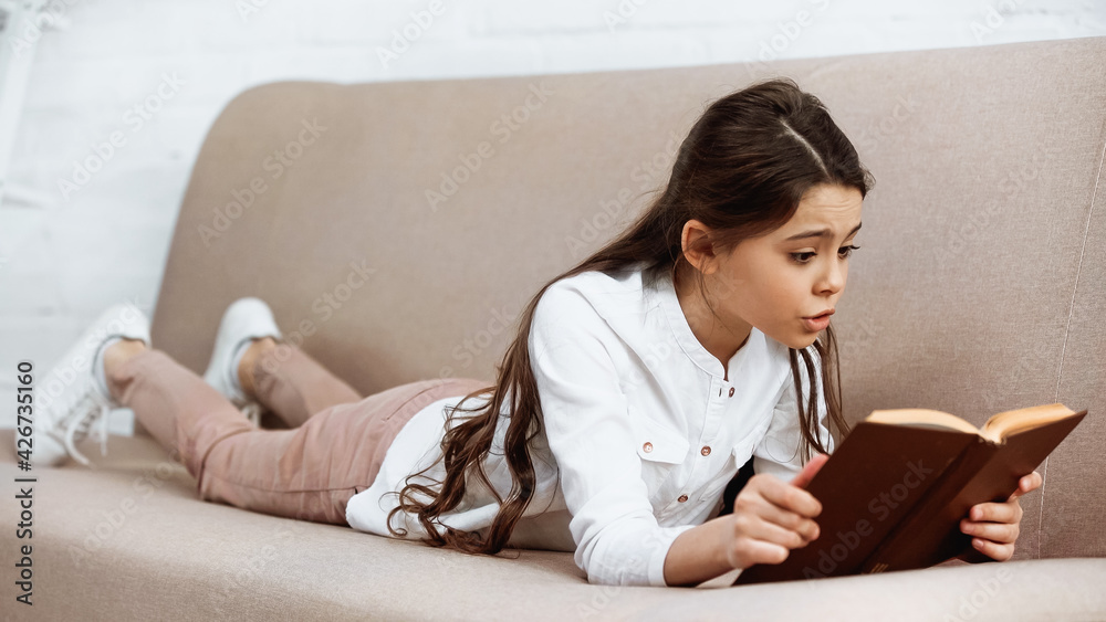 Preteen girl reading book on blurred foreground at home. Preteen girl reading book on blurred foreground at home.