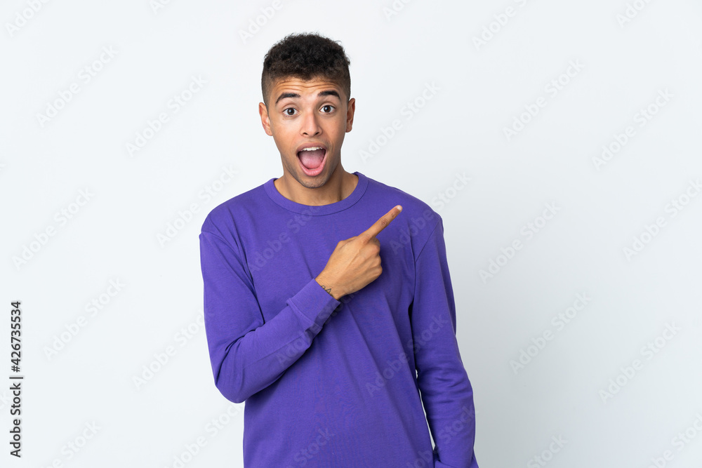 Young brazilian man isolated on white background surprised and pointing side Young brazilian man isolated on white background surprised and pointing side