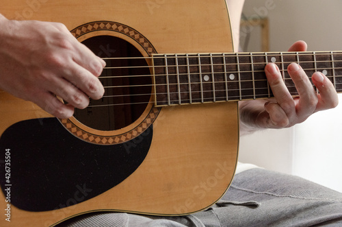 closeup on male hands playing acoustic guitar strings