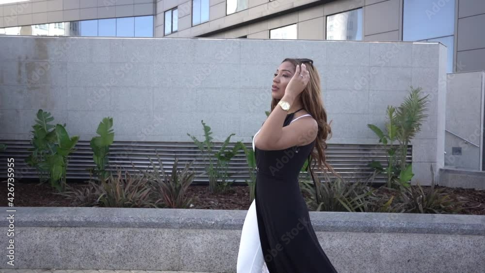 Young Latina walking through the city with buildings on a sunny day. Young Latina walking through the city with buildings on a sunny day.
