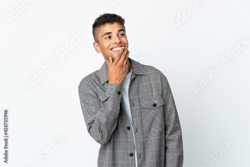 Young brazilian man isolated on white background looking up while smiling