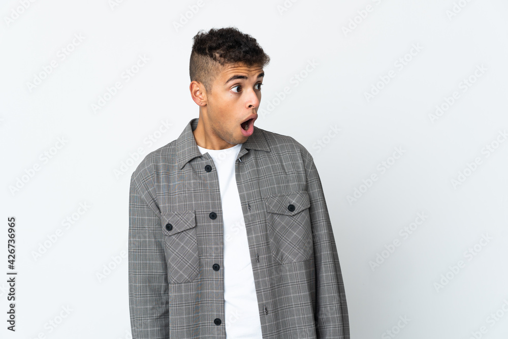 Young brazilian man isolated on white background doing surprise gesture while looking to the side Young brazilian man isolated on white background doing surprise gesture while looking to the side