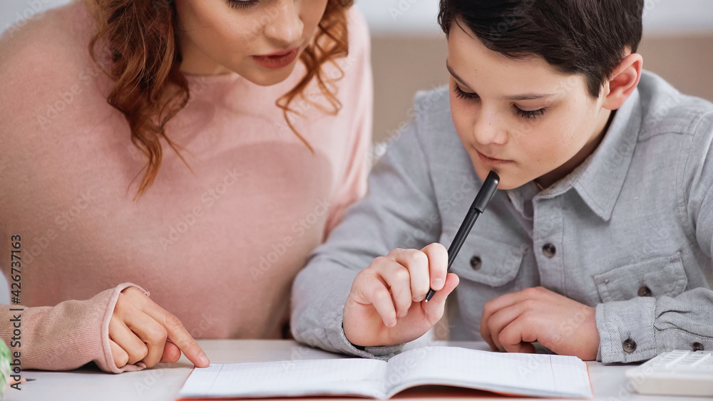 Mother sitting near child with pen doing homework. Mother sitting near child with pen doing homework.