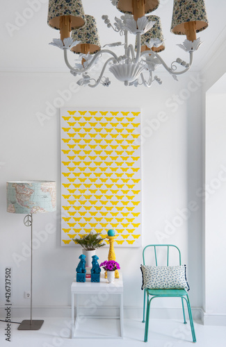 recanto de casa minimal e com cor. quadro com borbotas, cadeira verde água, mesa pequena com objectos decorativos, flores, candeeiro de tecto romântico com florzinhas, candeeiro de pé com mapa mundo photo