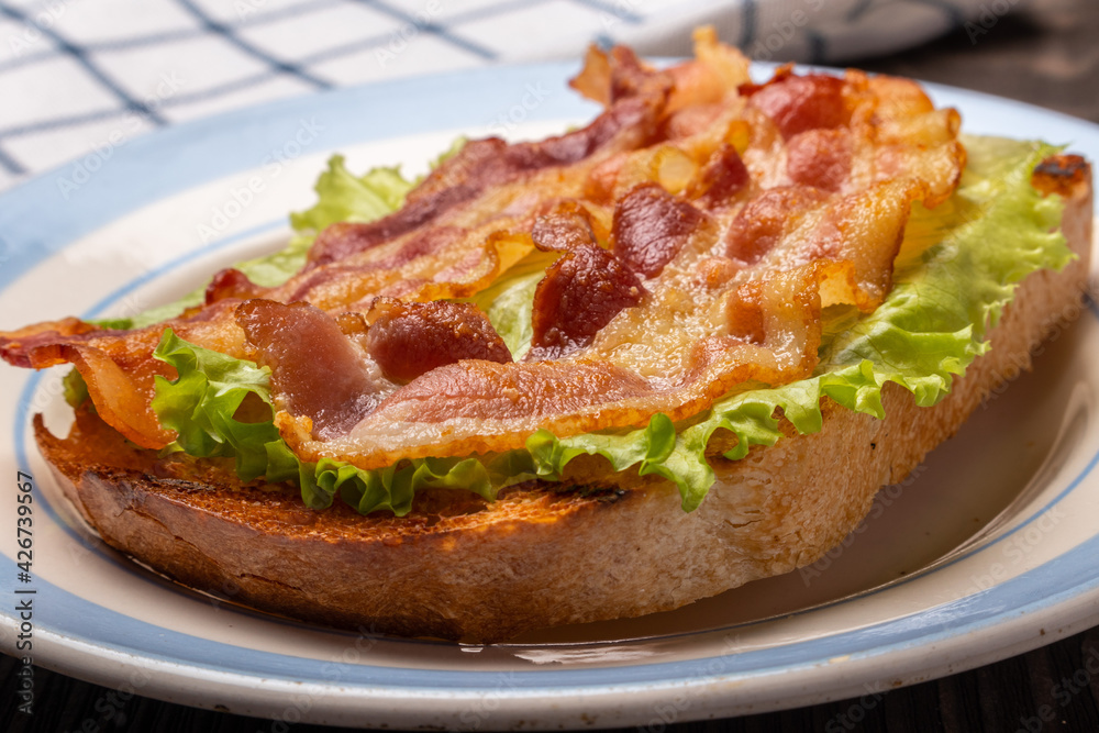 sandwich with fried bacon on a lettuce leaf closeup sandwich with fried bacon on a lettuce leaf closeup