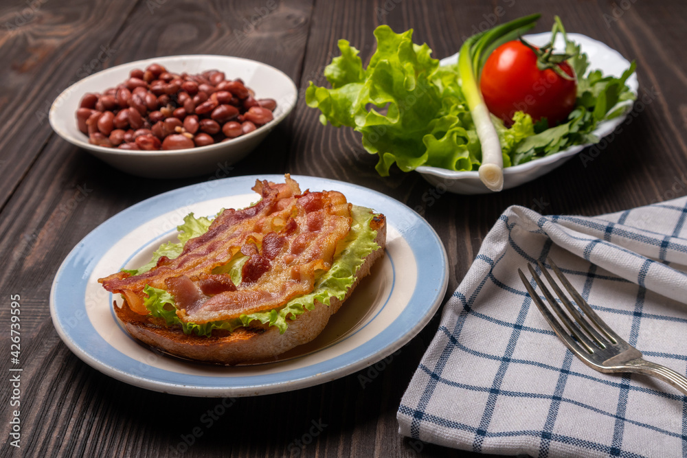 breakfast with a sandwich with fried bacon, beans and lettuce