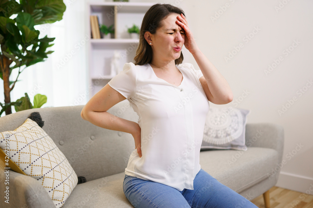 close up of unhappy woman suffering from pain in back or reins at home close up of unhappy woman suffering from pain in back or reins at home