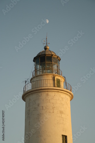 Atardeciendo con la luna alineada con el faro al pie del mar