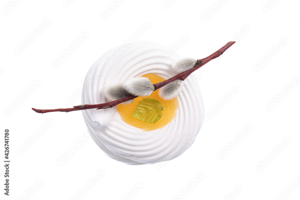 White meringue cookie with yellow lemon cream in the middle decorated with a stick from a willow tree isolated on white. Easter theme White meringue cookie with yellow lemon cream in the middle decorated with a stick from a willow tree isolated on white. Easter theme