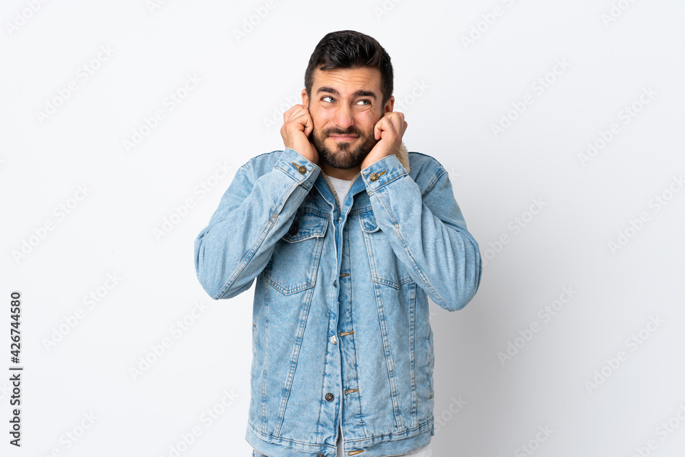 Young handsome man with beard isolated on white background frustrated and covering ears Young handsome man with beard isolated on white background frustrated and covering ears