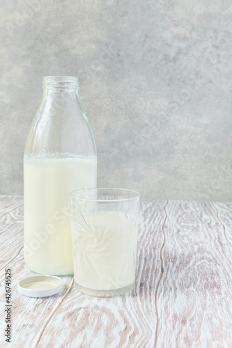 Milk in bottle and glass. In front of gray background. With copy space