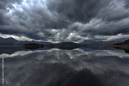 Rolling storm clouds and West Coast Range mountains reflect in Lake Burbury in Tasmania, Australia photo