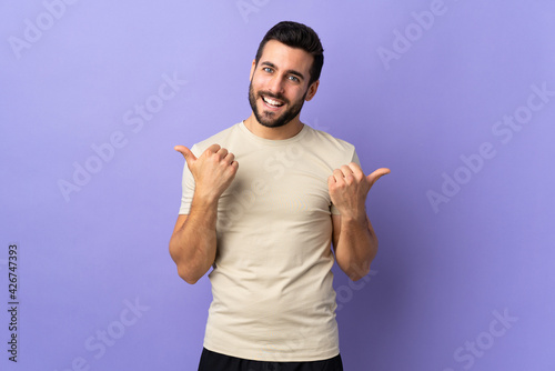 Young handsome man with beard over isolated background with thumbs up gesture and smiling