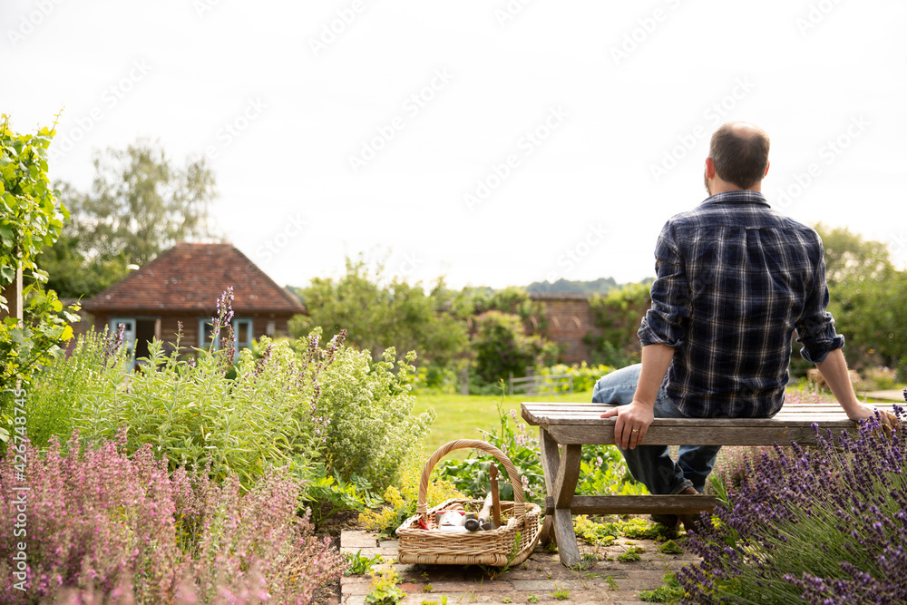 Man taking a break from gardening in idyllic sunny cottage garden
