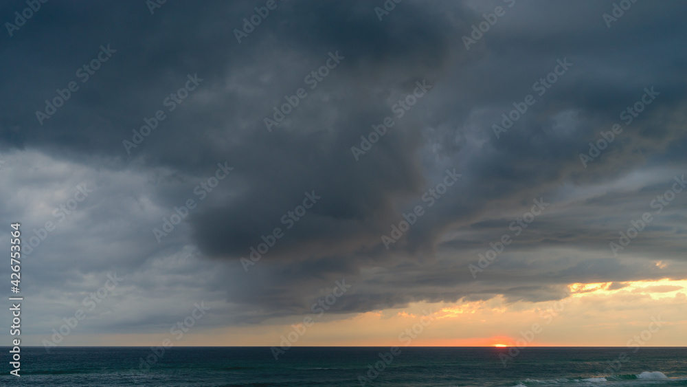 Sunset with dramatic dark storm clouds over the ocean