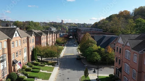 Flying along a street lined with brick facade town houses and a refurbished old factory in a regentrified neighborhood Woodbury in Baltimore Maryland USA