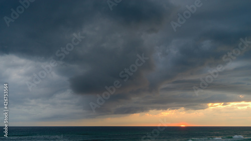 Sunset with dramatic dark storm clouds over the ocean