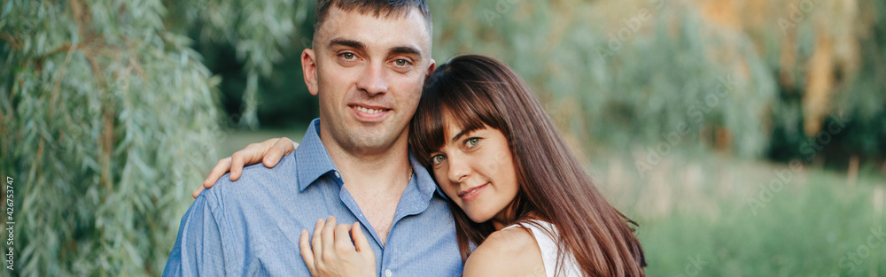 Married couple man woman in love. Husband and wife hugging in park on summer day at sunset. Togetherness and happiness. Authentic real people family outdoor. Web banner header. Married couple man woman in love. Husband and wife hugging in park on summer day at sunset. Togetherness and happiness. Authentic real people family outdoor. Web banner header.