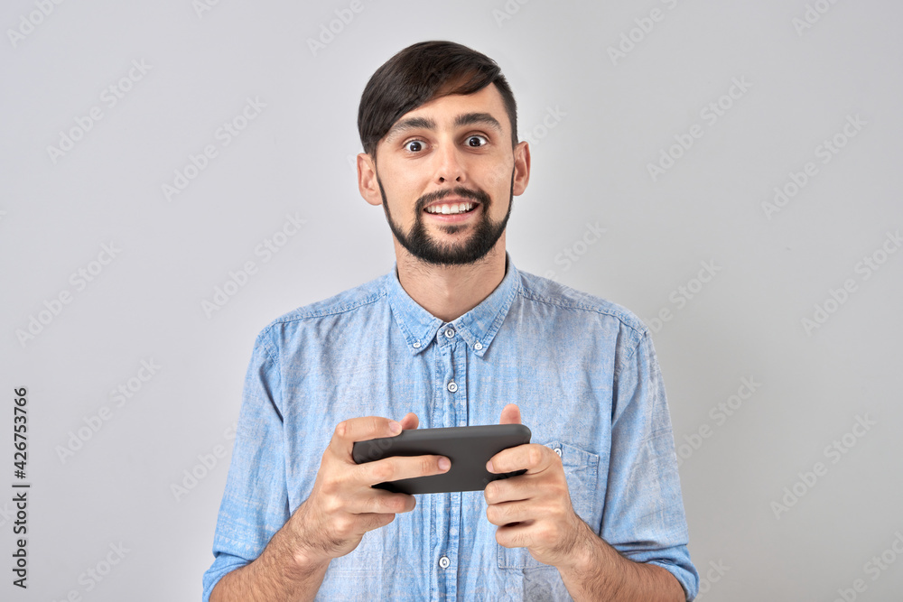 Young man playing games on smartphone isolated on studio background. Internet addiction concept Young man playing games on smartphone isolated on studio background. Internet addiction concept