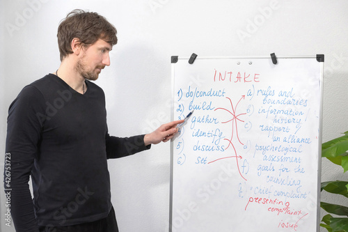 Concept of Online Education. Young English Teacher Standing and Pointing To the Board. A man holds an online lesson with students