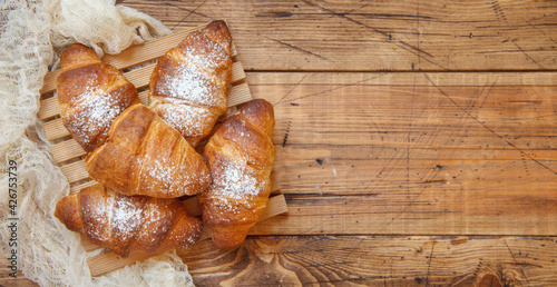 French fresh crusty croissants on a wooden table top view