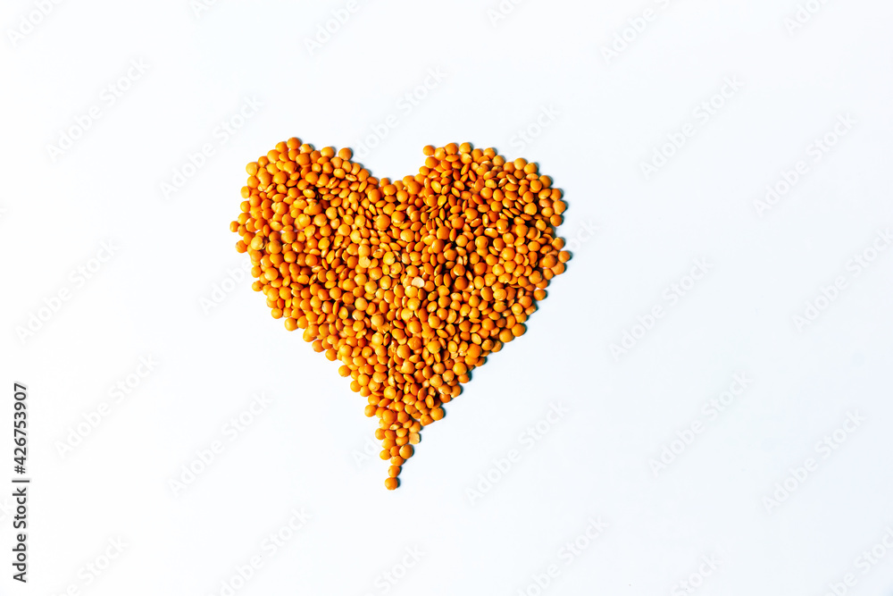 Red lentils seeds heap in heart shape on white background. Red lentils seeds heap in heart shape on white background.