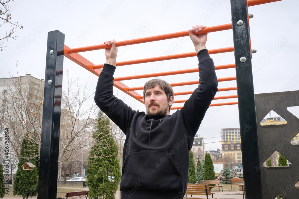 Young man doing pull-up exercises on the playground. Concept of sport and healthy lifestyle Young man doing pull-up exercises on the playground. Concept of sport and healthy lifestyle
