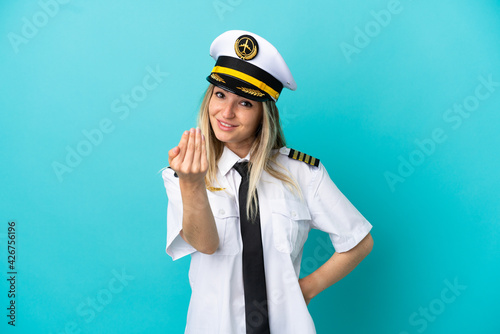 Airplane pilot over isolated blue background inviting to come with hand. Happy that you came