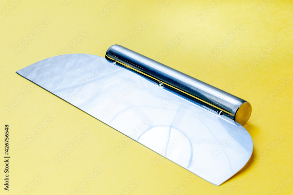 Metal Dough Scraper Knife Over Bright Yellow Surface Background