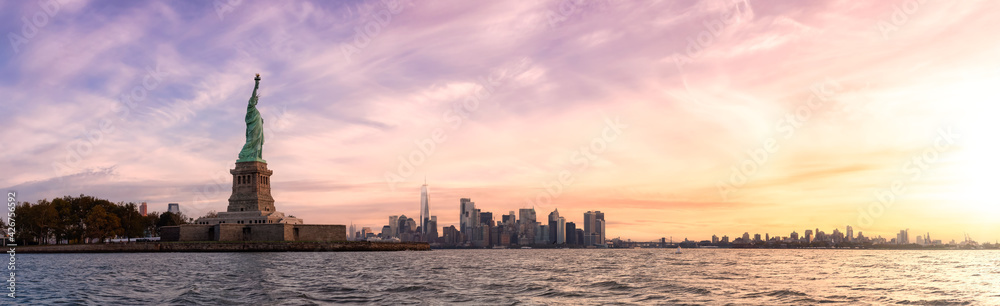 Panoramic view of the Statue of Liberty and Downtown Manhattan in the background. Dramatic Colorful Sunrise Artistic Render. Taken in Jersey City, New Jersey, United States.