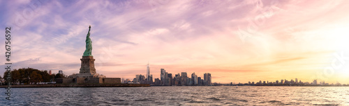 Panoramic view of the Statue of Liberty and Downtown Manhattan in the background. Dramatic Colorful Sunrise Artistic Render. Taken in Jersey City, New Jersey, United States. © edb3_16