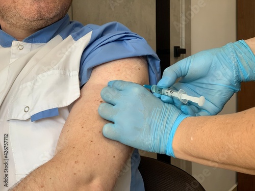 Doctor giving injection of covid-19 vaccine into patient's shoulder. Close-up.
