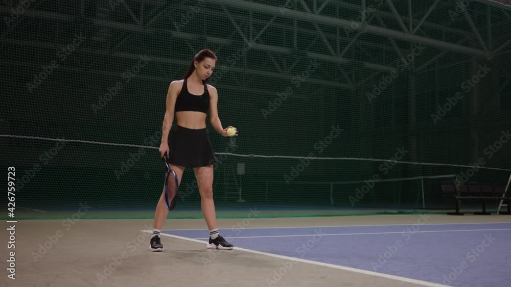 professional female tennis player is dressed sportswear is throwing ball on court before serving, full-length portrait