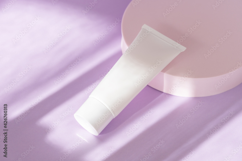 Obraz premium Skin care cosmetic bottle mockup on lilac podium. Facial cream, moisturizer, lotion jar plastic tube on background with natural shadows, high angle view. Brand spa packaging mock up. Branding identity