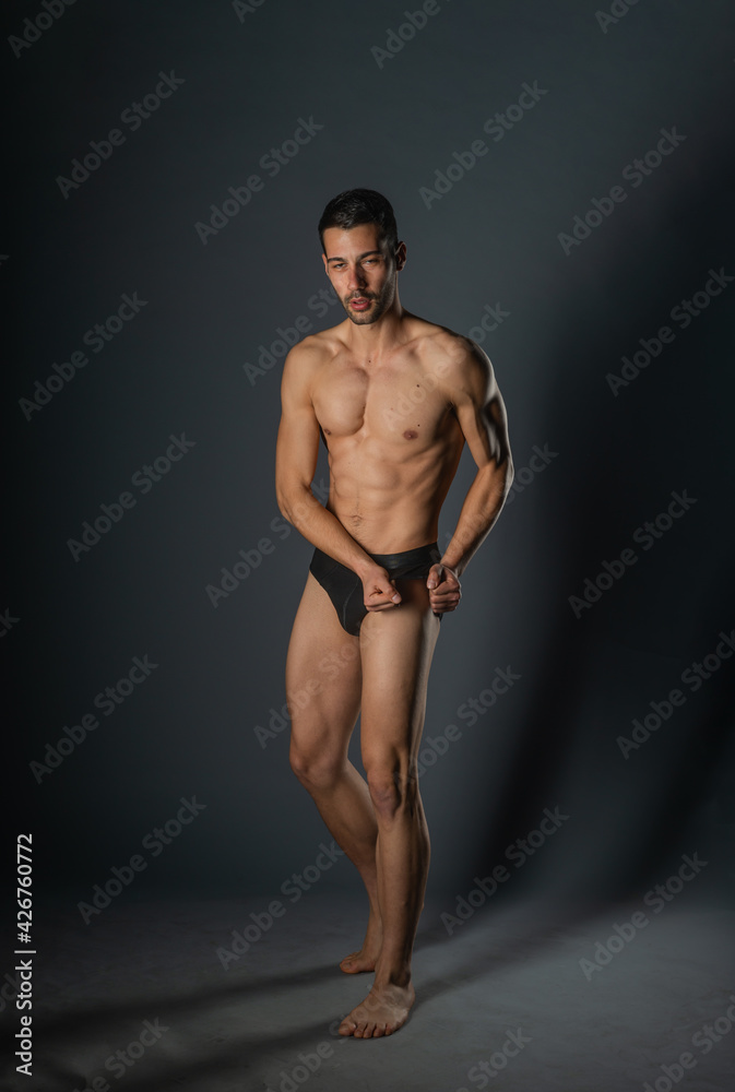 Naklejka premium Sexy man with a muscular body posing naked with black underpants inside a studio