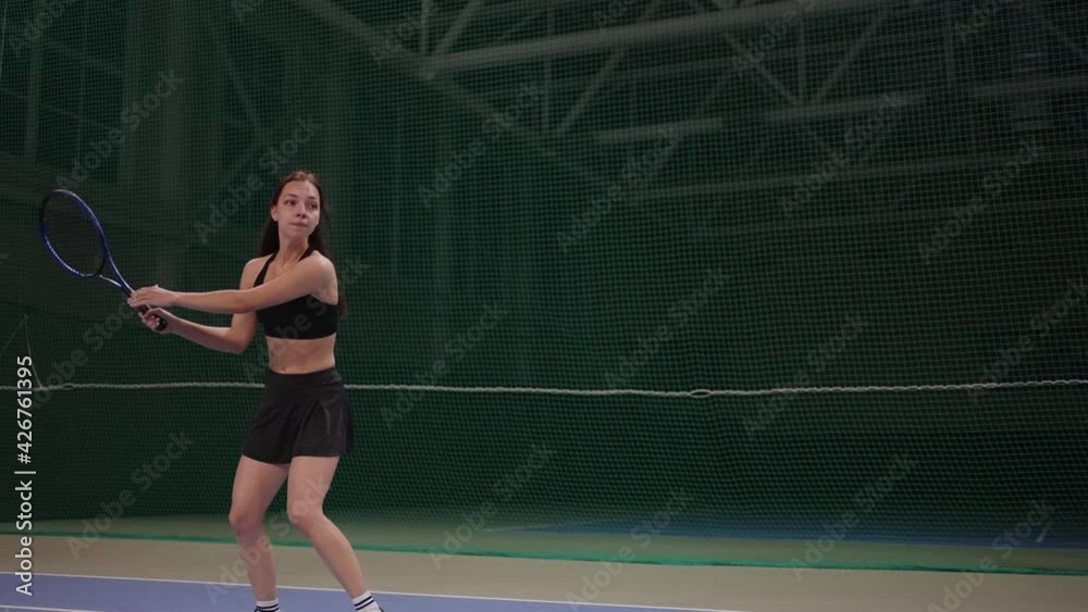 young woman is playing tennis on indoor court, hitting ball by racquet, slow motion inside game young woman is playing tennis on indoor court, hitting ball by racquet, slow motion inside game