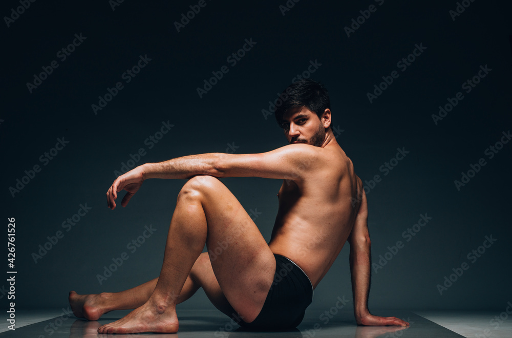 Cheerful young man in trunks over dark background Cheerful young man in trunks over dark background