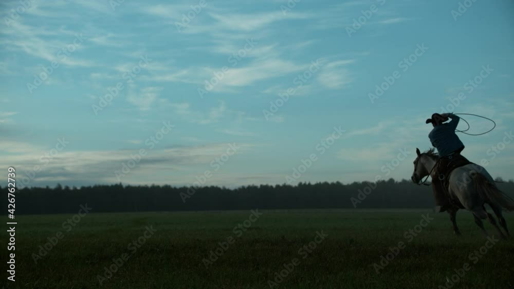 Rancher Man Riding Horse and Lassoing on Farm. Guy Ride Domestic Animal and Waving Rope above Head, Rodeo Exercise Making on Meadow at Sunrise. Boy Active Time Tracking Shot Slowmotion Rancher Man Riding Horse and Lassoing on Farm. Guy Ride Domestic Animal and Waving Rope above Head, Rodeo Exercise Making on Meadow at Sunrise. Boy Active Time Tracking Shot Slowmotion