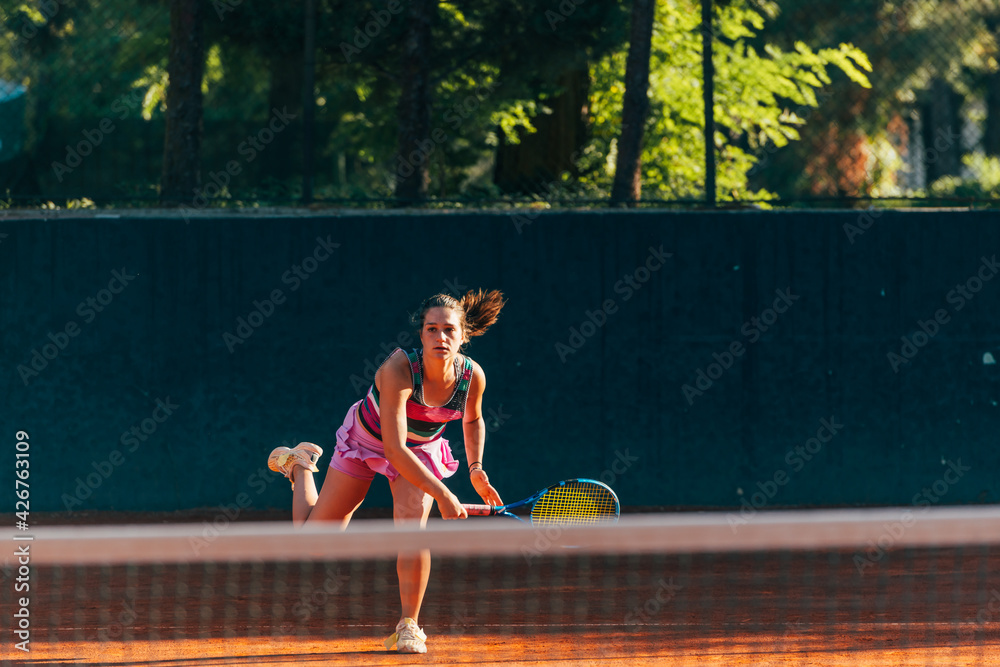 Obraz premium Professional equipped female tennis player serving the tennis ball on a sunny day