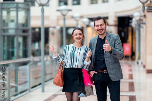 Modern looking smiling couple in a shopping mall, they are gesturing okay sign and they are happy