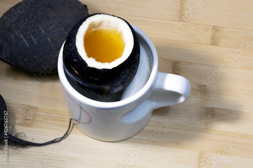 Homemade black radish and honey cough syrup. Close-up on a wooden table in a mug.