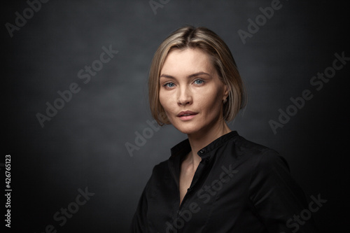 Beautiful middle-aged woman on a gray background in a black blouse.