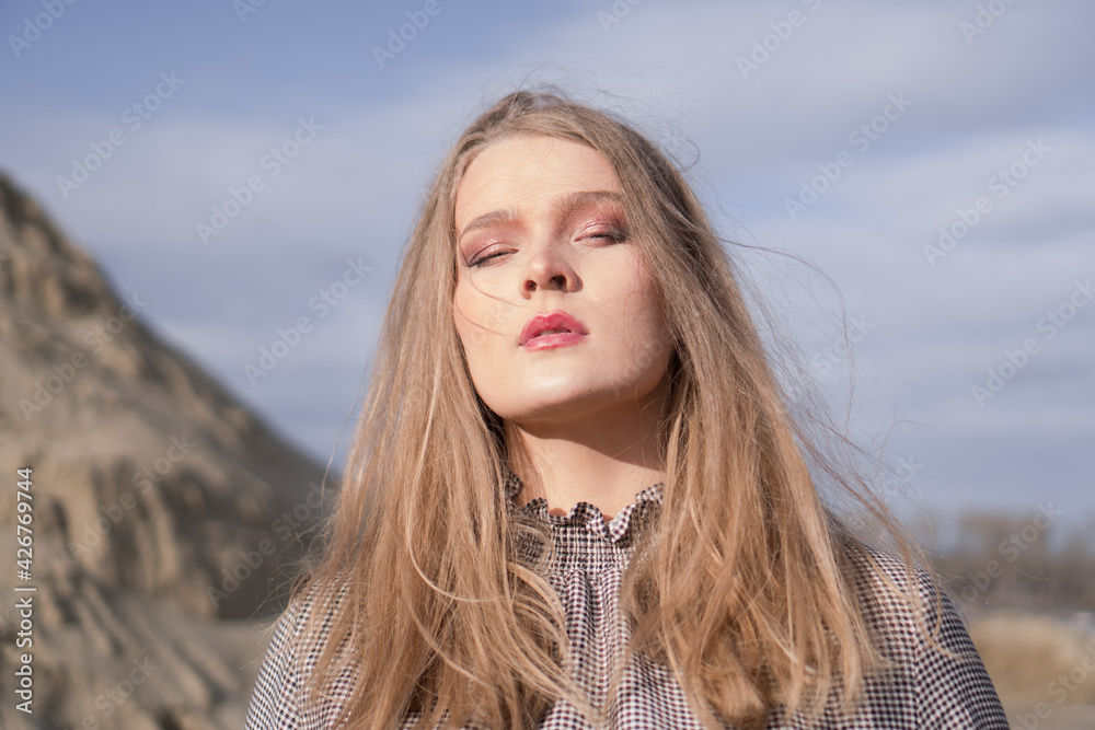 Beauty portrait of a young blond girl in a vintage dress. She is posing on a sandy landscape. Beauty portrait of a young blond girl in a vintage dress. She is posing on a sandy landscape.