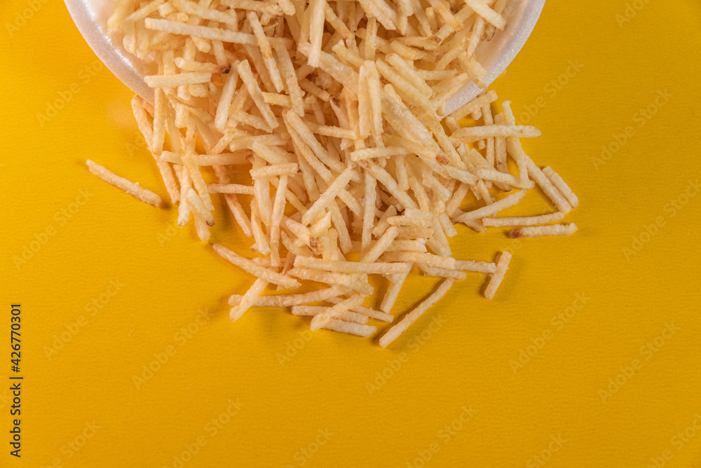 White bowl with potato straw on yellow background