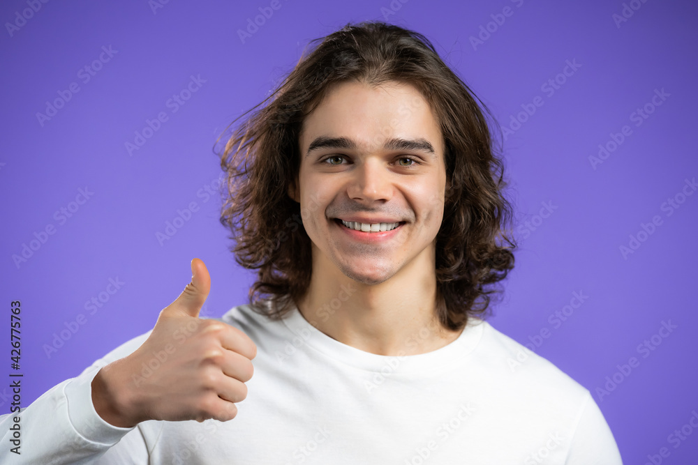 Handsome man shows thumb up, Like gesture. Happy guy on violet background. Winner. Success. Positive male model smiles to camera. Body language. Handsome man shows thumb up, Like gesture. Happy guy on violet background. Winner. Success. Positive male model smiles to camera. Body language.
