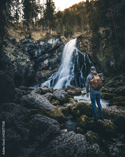 man with backpack standing in front of waterfall