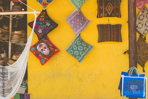 A yellow wall with handmade artisanal pillows and blankets displayed at a souvenir store in Tulum in Mexico